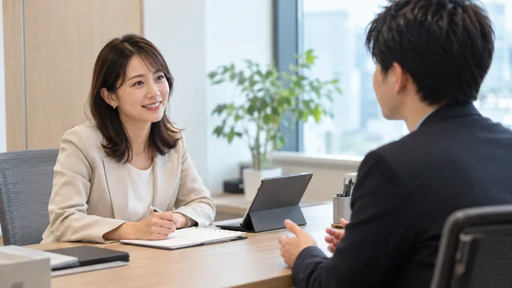 面談室で、キャリアアドバイザーが求職者の話を笑顔で聞いている